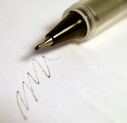 The point of a pen with scribbles on paper.