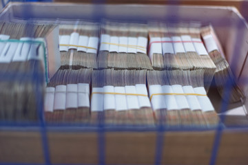 Bank employees sorting and counting money inside bank vault.