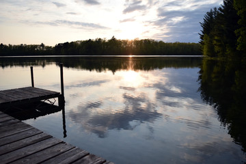 Fototapeta na wymiar Sunset over a lake with a dock on the side.