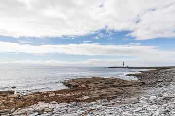 Rocks and beach with lighthouse in background in Inisheer island