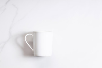 White ceramic cup of hot cocoa on top of white marble background
