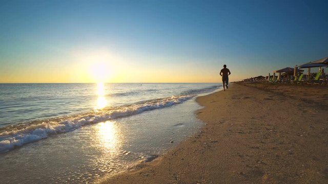 Man running on the beach at sunse