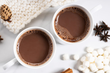 White ceramic cups of hot cocoa on top of white marble background, top view