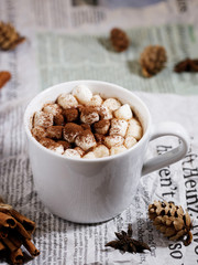 White ceramic cups of hot cocoa with marshmallows on top of rustic paper background