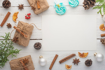 Christmas frame. Postcard with Christmas tree branch and gifts, on white wooden background.