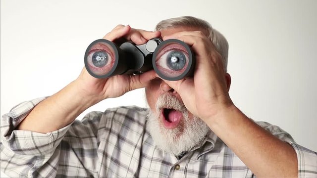 Senior adult male looking through binoculars with a surprised expression on his face. 