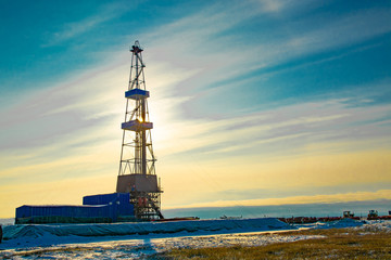 Oil and gas drilling rig in the northern tundra. The beginning of winter in the Arctic. The sun...