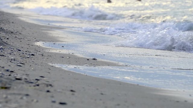 ow point of view over an out-of-focus pebbled beach with a splashing wave, background loop
