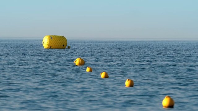 Protective floats buoy on the rope on the beach in the water, selective focus
