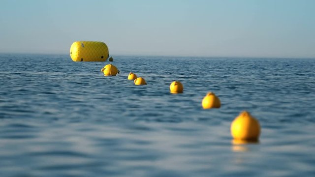 Protective floats on the rope on the beach in the water, selective focus