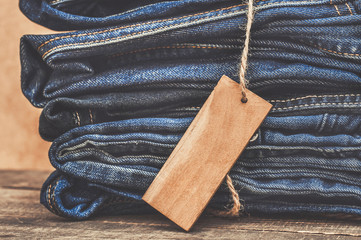 Stack of blue jeans with a wooden label as a background or advertisement a denim clothing