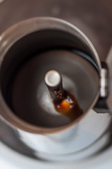 The first stream of fresh coffee flows from the spout of the coffee maker under pressure.