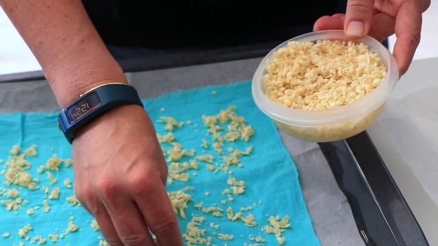 Making a bee wrap, zero waste solution replacing plastic wrap, made from beeswax and blue textile. Closeup on woman's hand. Spread on baking sheet. Healthy & organic lifestyle. Holiday kids activity. 