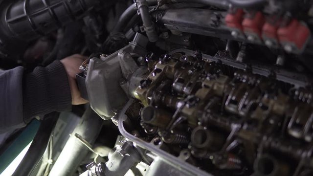 Mechanic hands tighten nut with wrench while repairing engine