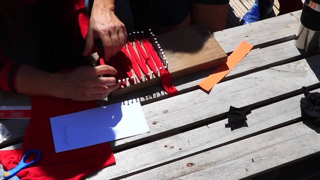 Leisure activity to create an eco-friendly tawashi sponge, with a homemade weaving loom from wood and nails. Red and black handcraft. Family, children activity. Shared team work, together. Happy day. 