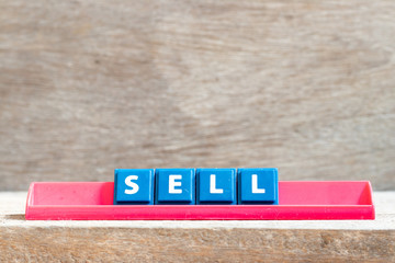 Tile letter on red rack in word sell on wood background