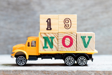Truck hold letter block in word 19nov on wood background (Concept for date 19 month November)