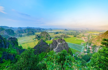 Aerial view of Ninh Binh region, Trang An Tam Coc tourist attraction, UNESCO World Heritage Site, Scenic river crawling through karst mountain ranges in Vietnam, travel destination.