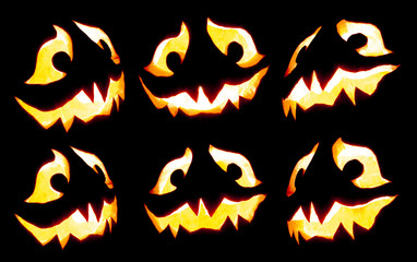 Collection of scary Halloween pumpkin Jack o lantern faces glowing red and yellow eerily on black