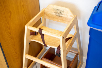 A view of a wooden kids high chair in a restaurant setting.