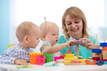 Obraz na płótnie Canvas Little caucasian baby playing with Montessori toy in creche or pre-school