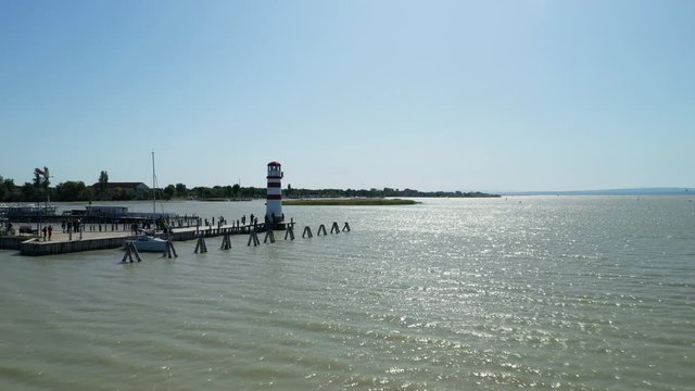 Aerial drone shot of a lighthouse on a lake. Camera moving forward towards an island.