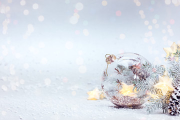 Fototapeta na wymiar winter snowy white background with fir tree branch, glass ball and glowing lights garland