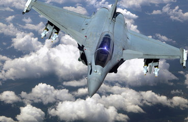 Military jet fighter flying above clouds
