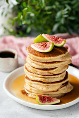 Pancakes with figs and honey. Stack of homemade fluffy buttermilk pancakes served with fresh sliced figs. Vertical orientation