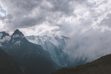 Mountains scene with dramatic cloudy sky in national park of Dombay