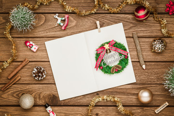 Top view of blank notebook on wood  background with xmas decorations. Mockup Christmas background with notebook for wish list or to do list. Flat lay with copy space.