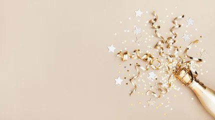 Fotobehang Vieringsachtergrond met gouden champagnefles, confettiensterren en partijwimpels. Kerstmis, verjaardag of bruiloft concept. Plat leggen. © juliasudnitskaya