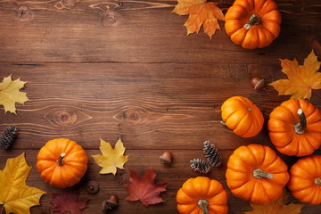 Autumn Thanksgiving background. Pumpkins, acorns and leaves on wooden board top view.