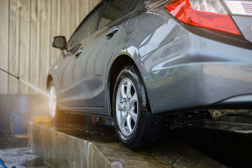 Washing the outside of the car. Cleaning grey car using high pressure water. This step is to wash after using foam to wipe the dirt.