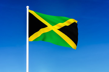 Waving flag of Jamaica on the blue sky background