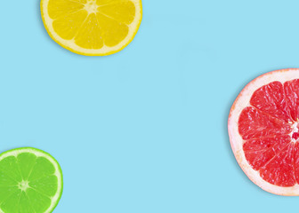 Fresh slices of grapefruit, lemon and lime on a blue background.
