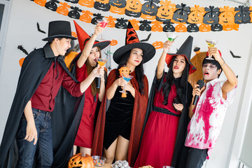 Obraz premium Gang of teen Asian celebrate Halloween for sing a song and drink, dessert in the room.