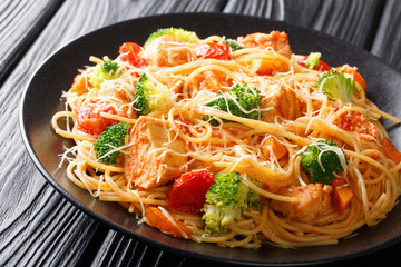 Tasty pasta with chicken and vegetables close-up on a plate. horizontal
