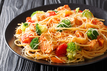 Pasta salad with broccoli, chicken, tomatoes, cheese and pumpkin close-up on a plate. horizontal