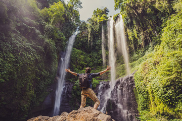 Man in turquoise dress at the Sekumpul waterfalls in jungles on Bali island, Indonesia. Bali Travel...