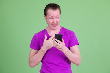 Portrait of happy young handsome man using phone