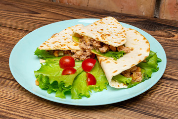 fajitos with minced meat vegetables in a corn tortilla on a blue plate dark wooden background. fast food traditional food concept