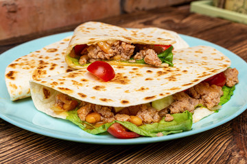 fajitos with minced meat vegetables in a corn tortilla on a blue plate dark wooden background. fast food traditional food concept