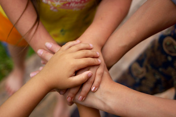 Lot of hands together one over the other. the concept of friendship, family relations. Four hands of the family, a baby, a daughter, a mother and a father. Concept of unity, support, protection and ha