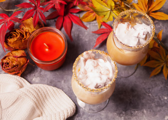 Obraz na płótnie Canvas Two glass of hot creamy cocoa with froth with autumn leaves and candle on the background
