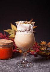 Two glass of hot creamy cocoa with froth with autumn leaves and pumpkins on the background