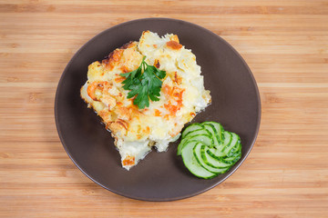 Cauliflower and seafood gratin portion on brown dish, top view