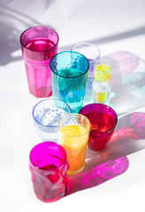 Glass goblets create wonderful coloured shadows on a solar table. The shadow of sunlight reflect to glass of pink and yellow, emerald colors.