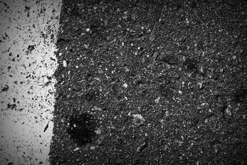 Old dirty asphalt surface with white paint on it. Top view black and white