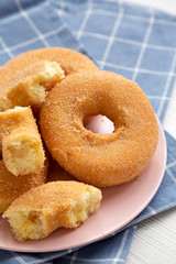 Homemade autumn apple-cinnamon donuts on a pink plate on a black background, side view. Close-up.